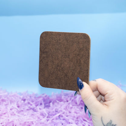 Showing Reverse of Square hard backed coaster featuring a colourful pattern of glossy pastel heart candies, set against a blue background with purple shredded paper.