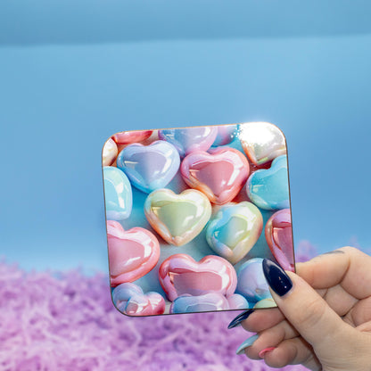 Square hard backed coaster featuring a colourful pattern of glossy pastel heart candies, set against a blue background with purple shredded paper.