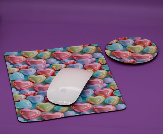 A rectangular desk mat and a round coaster, both printed with a colorful pattern of 3D-effect pastel hearts, shown on a solid purple background with a white computer mouse on the mat.