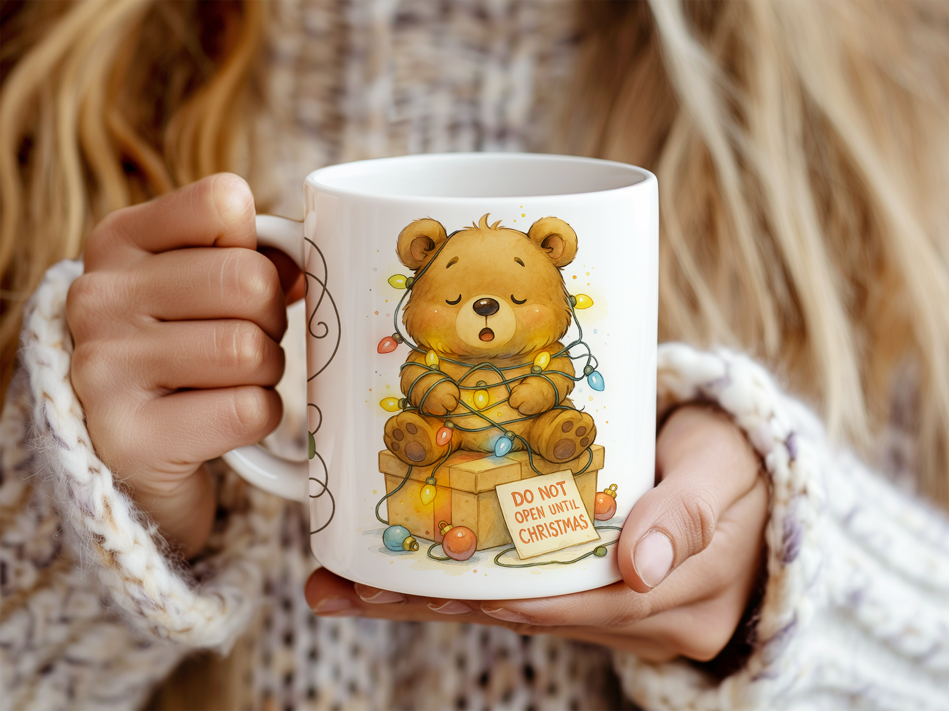 a white ceramic mug with a cute illustration of a teddy bear wrapped in Christmas lights and a gift box, with the text 'DO NOT OPEN WITH CHRISTMAS'.