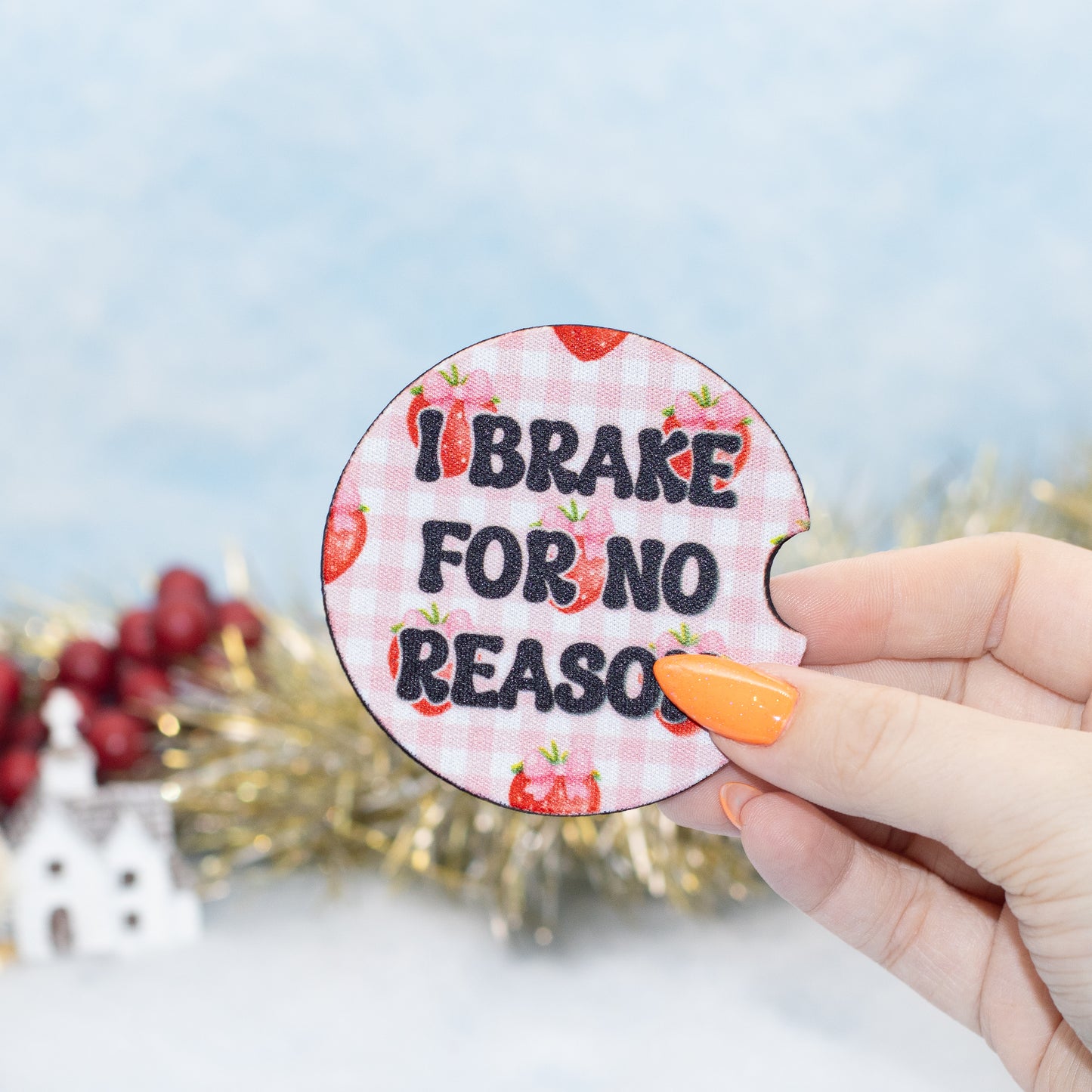 A hand holds a round coaster featuring a pink and white gingham pattern, strawberries, and the text 'I BRAKE FOR NO REASON' in black letters. 