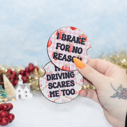 A hand hold two car coasters with a strawberry and pink gingham pattern. The stickers feature the text 'I BRAKE FOR NO REASON' and MY DRIVING SCARES ME TOO'.