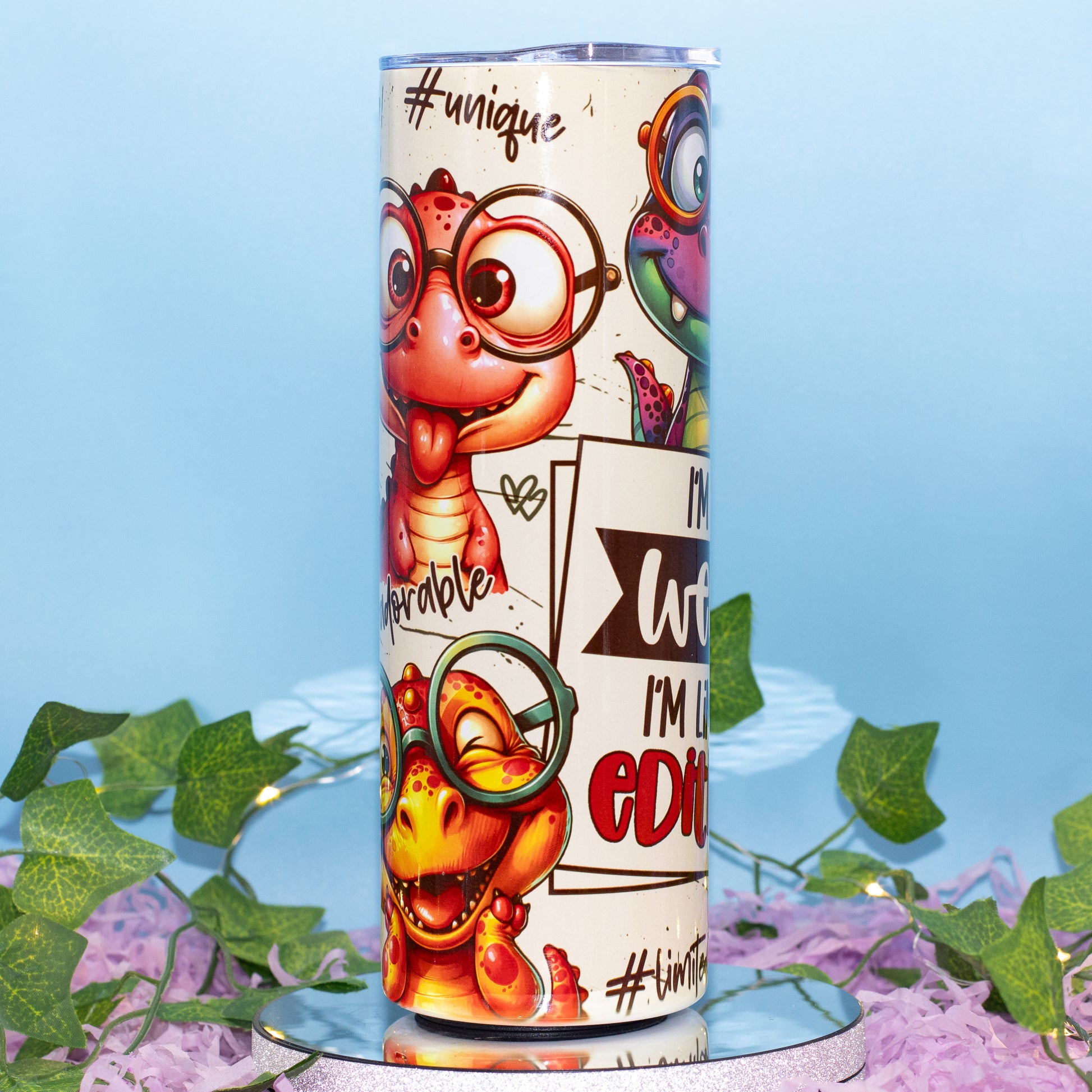 A custom printed tumbler cup featuring cartoon dinosaur characters wearing glasses 