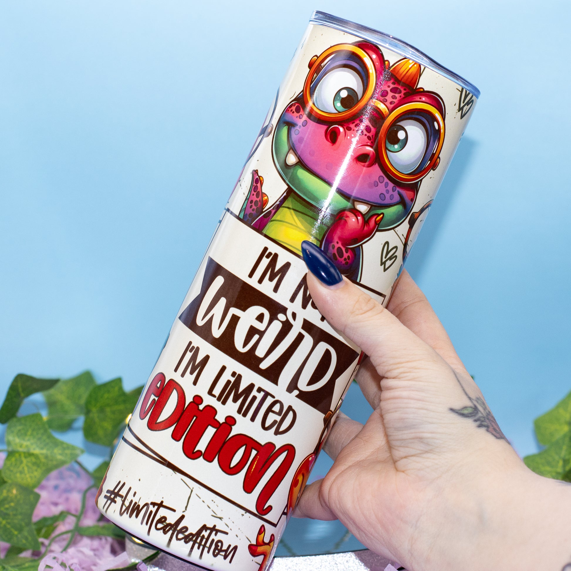 A hand holds a cylindrical plastic container featuring a colourful cartoon dino and the text 'I'M NOT weird, I'M LIMITED EDITION' 