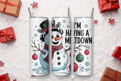 tall white insulated tumblers with metal straws are arranged on a white surface with holiday gift boxes around them. The tumblers feature Christmas-themed graphics: a snowman on the left, a smiling snowman face in the center, and a tree branch with ornaments and the text 'I'M HAVING A MELTDOWN' on the right.