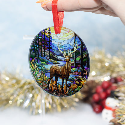 A hand holds a round glass Christmas ornament featuring a stained-glass-style forest scene with a deer, suspended by a red ribbon. The background is softly blurred with gold tinsel and red berries.