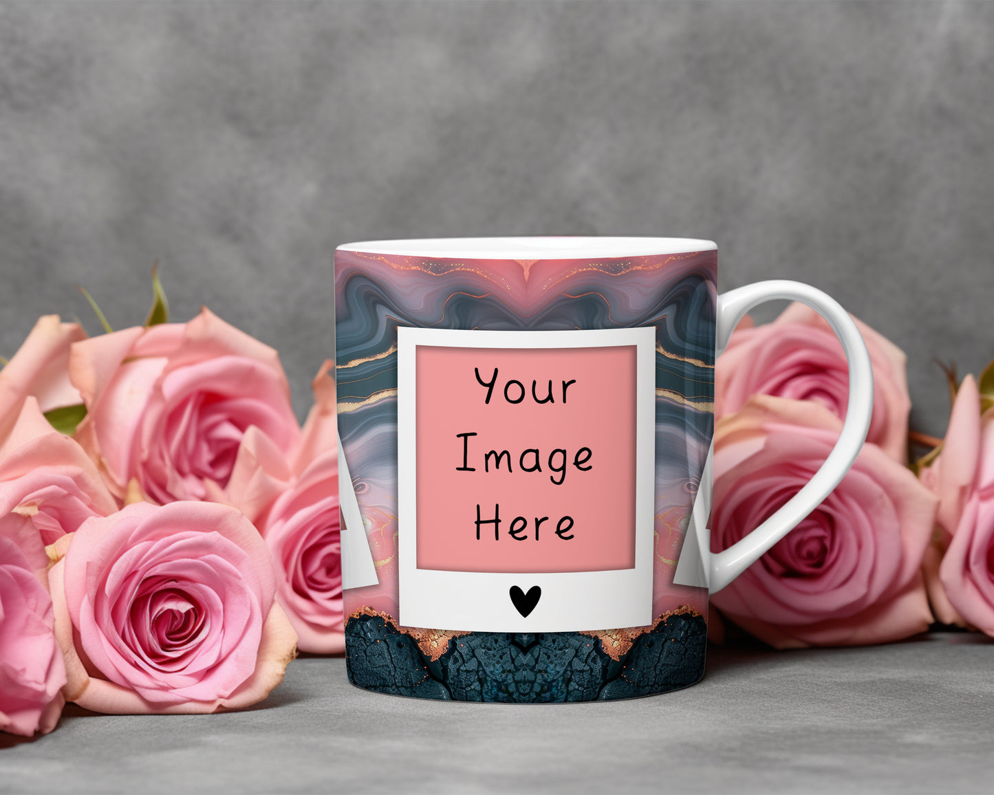 A white ceramic mug with a pink, blue, and gold marbled pattern, featuring a customizable photo frame design with the text 'Your Image Here' and a small black heart. The mug is styled with pink roses on a gray surface against a textured gray background.
