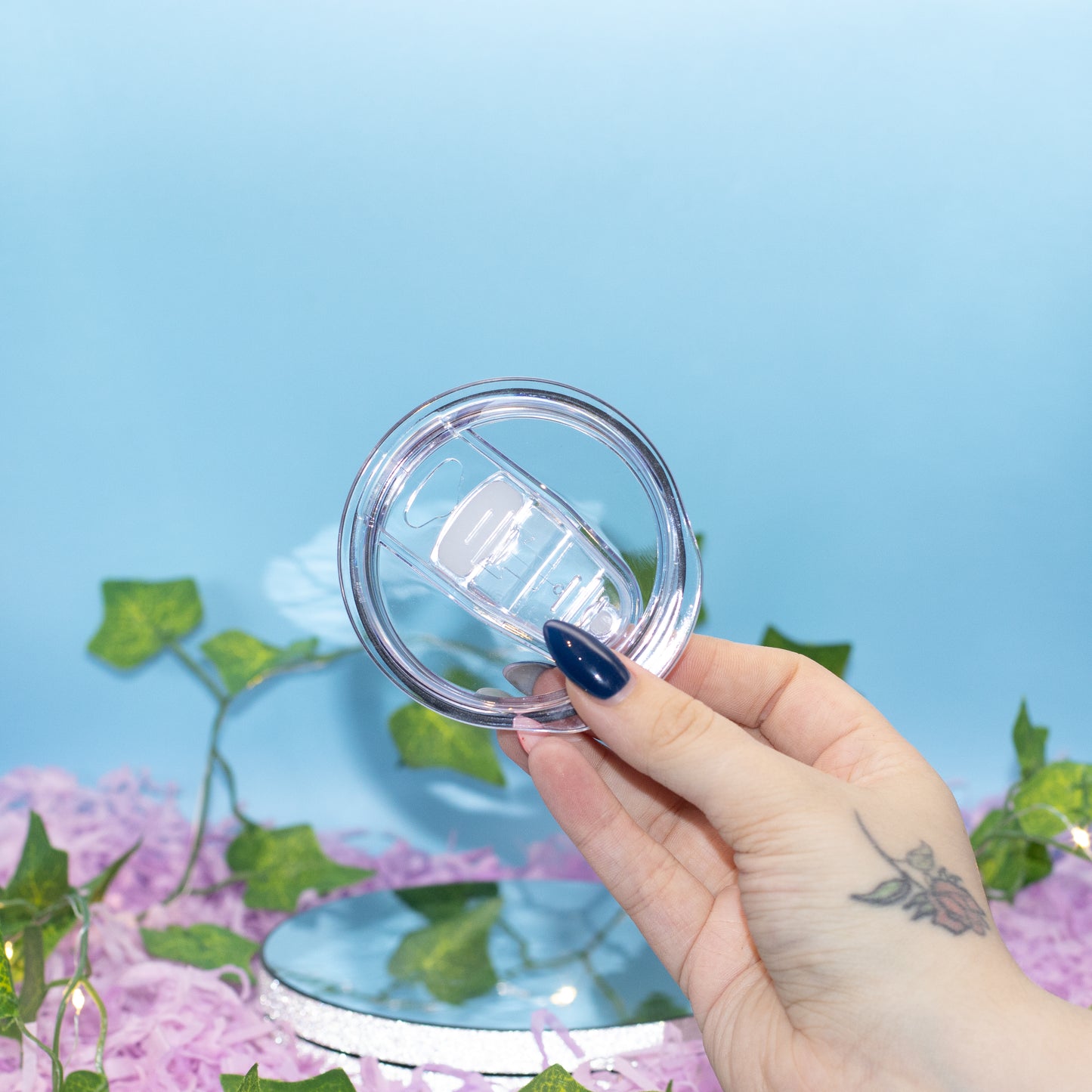 A hand holds a clear plastic lid with a slid top 