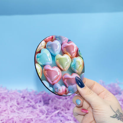 Round coaster featuring a colourful pattern of glossy heart-shaped candy set against a light blue background 