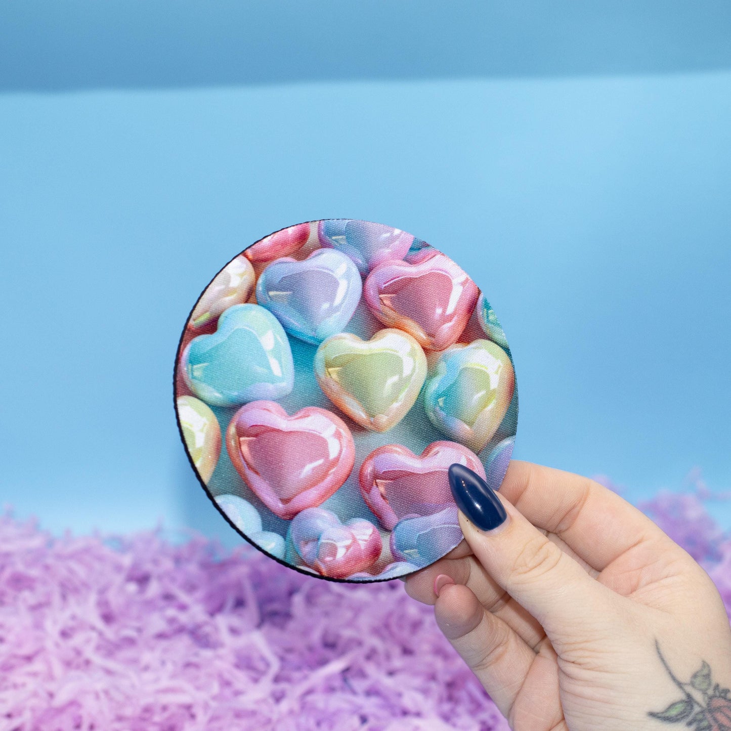 Round coaster featuring a colourful pattern of glossy heart-shaped candy set against a light blue background 