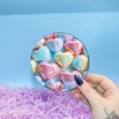 Round coaster featuring a colourful pattern of glossy heart-shaped candy set against a light blue background 