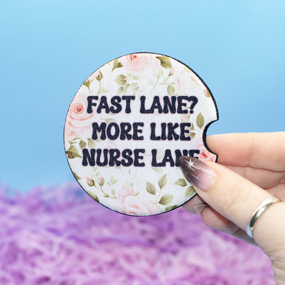A hand holds a round embroidered patch with a floral design and the text 'FAST LANE? MORE LIKE NURSE LANE!' against a blue and purple background.
