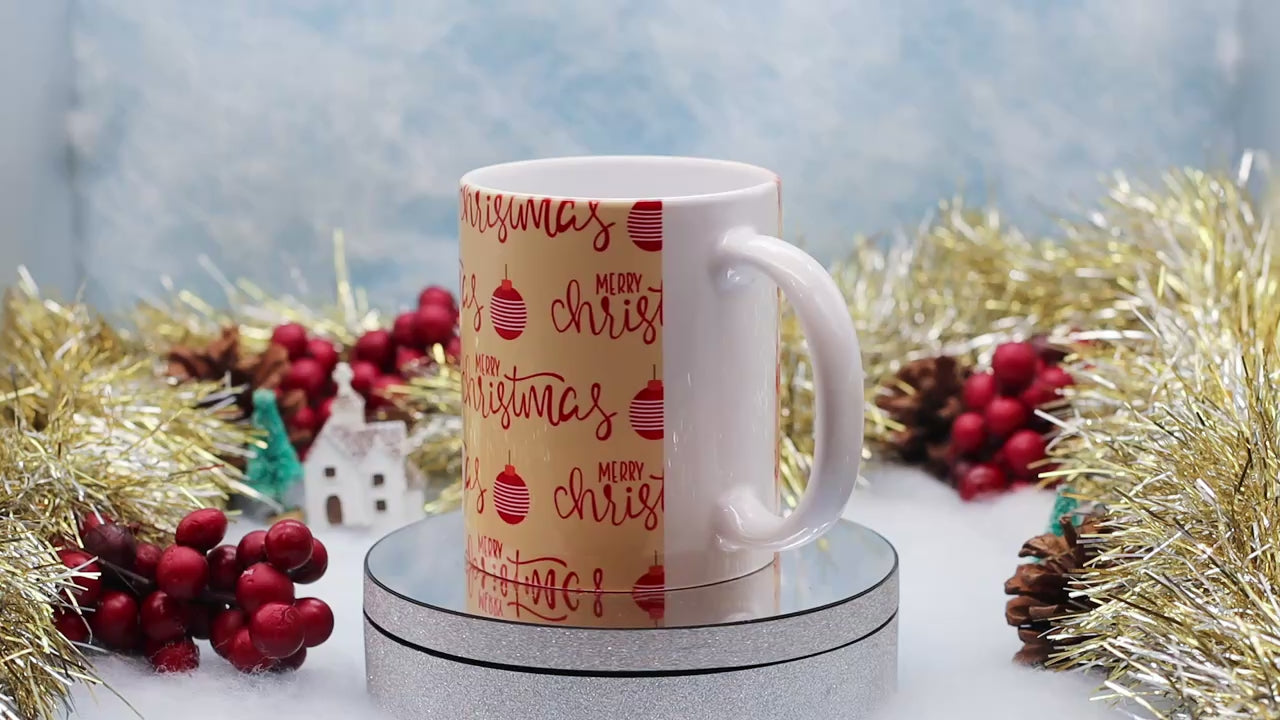 Video showing A ceramic mug wrapped in festive Christmas paper with 'Merry Christmas' and red ornaments,