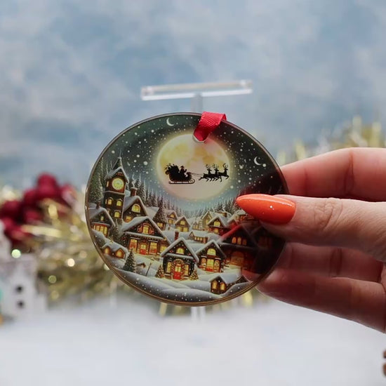 Video showcasing a glass frosted Christmas ornament featuring a Santa slay over a snowy town