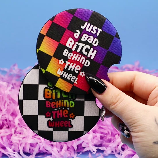 Video showcasing two checkerboard car coasters with the words Just A Bad Bitch Behind the Wheel
