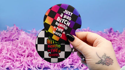 Video showcasing two checkerboard car coasters with the words Just A Bad Bitch Behind the Wheel