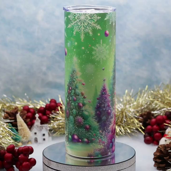 Video Showcasing A tall Stainless Steel Tumbler featuring a colourful printed Christmas tree design with pink, purple, and green ornaments, set on a silver pedestal with holiday decorations in the background.