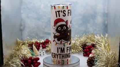 Video Showcasing A tall insulated tumbler with a clear lid, featuring a cartoon black cat in a red Santa hat and the text 'IT'S FINE I'M FINE EVERYTHING IS FINE' with holiday lights, 