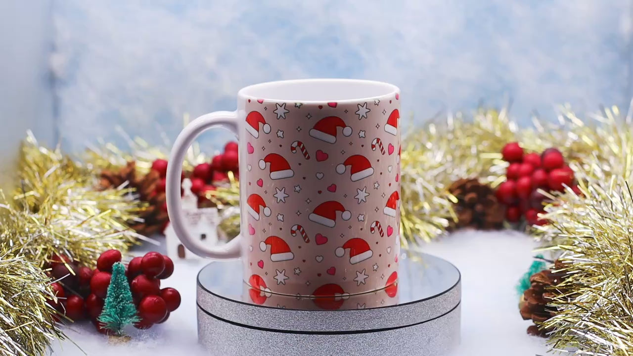 Video showcasing A white ceramic mug decorated with a festive Christmas pattern of Santa hats, candy canes, hearts, and stars,