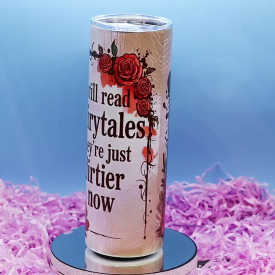 video showcasing A tall insulated tumbler with a clear lid, featuring the printed phrase 'I still read fairytales they're just dirtier now' 