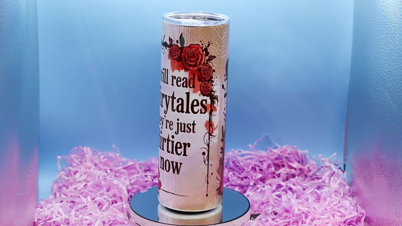 video showcasing A tall insulated tumbler with a clear lid, featuring the printed phrase 'I still read fairytales they're just dirtier now' 