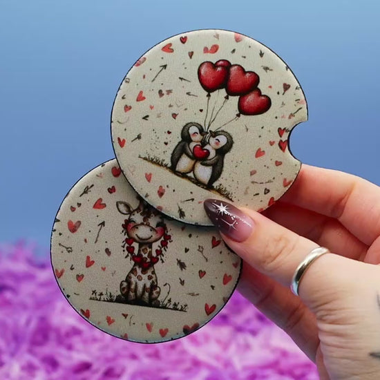 Video showcasing two car coasters, one with a valentine penguin and the other with a valentine giraffe