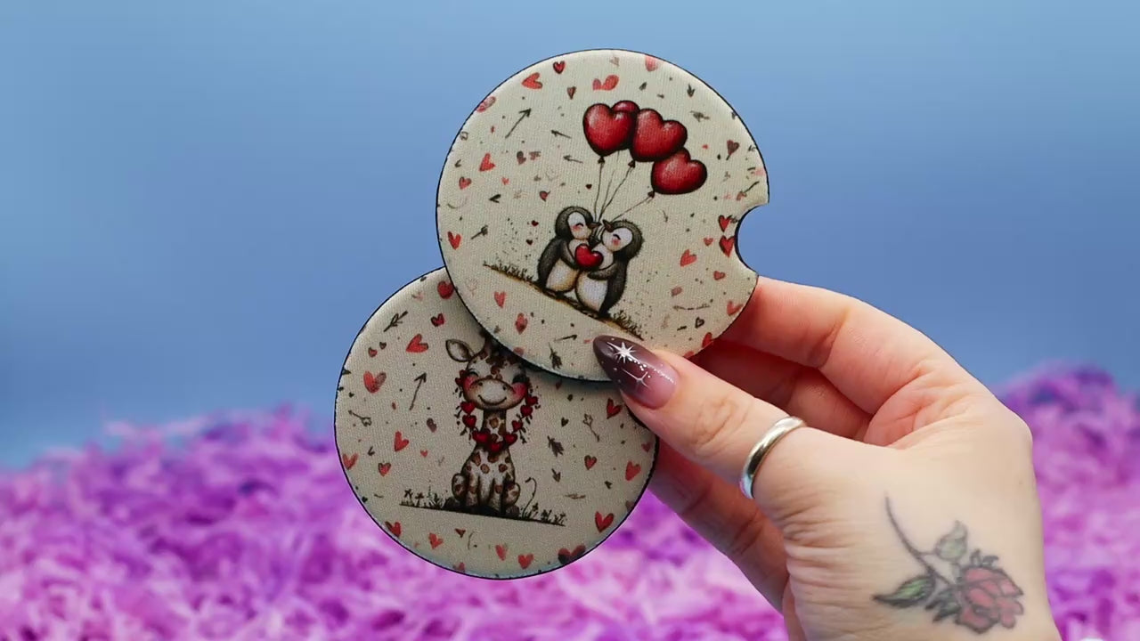 Video showcasing two car coasters, one with a valentine penguin and the other with a valentine giraffe